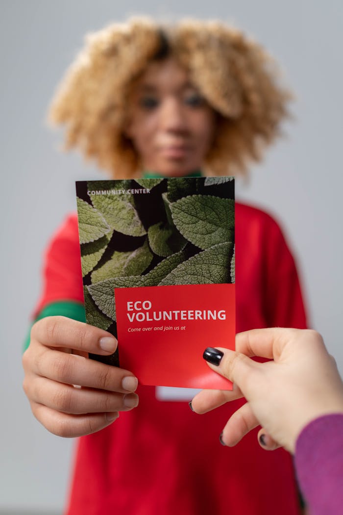 Close-up of a person handing out an eco volunteering flyer, promoting community service.